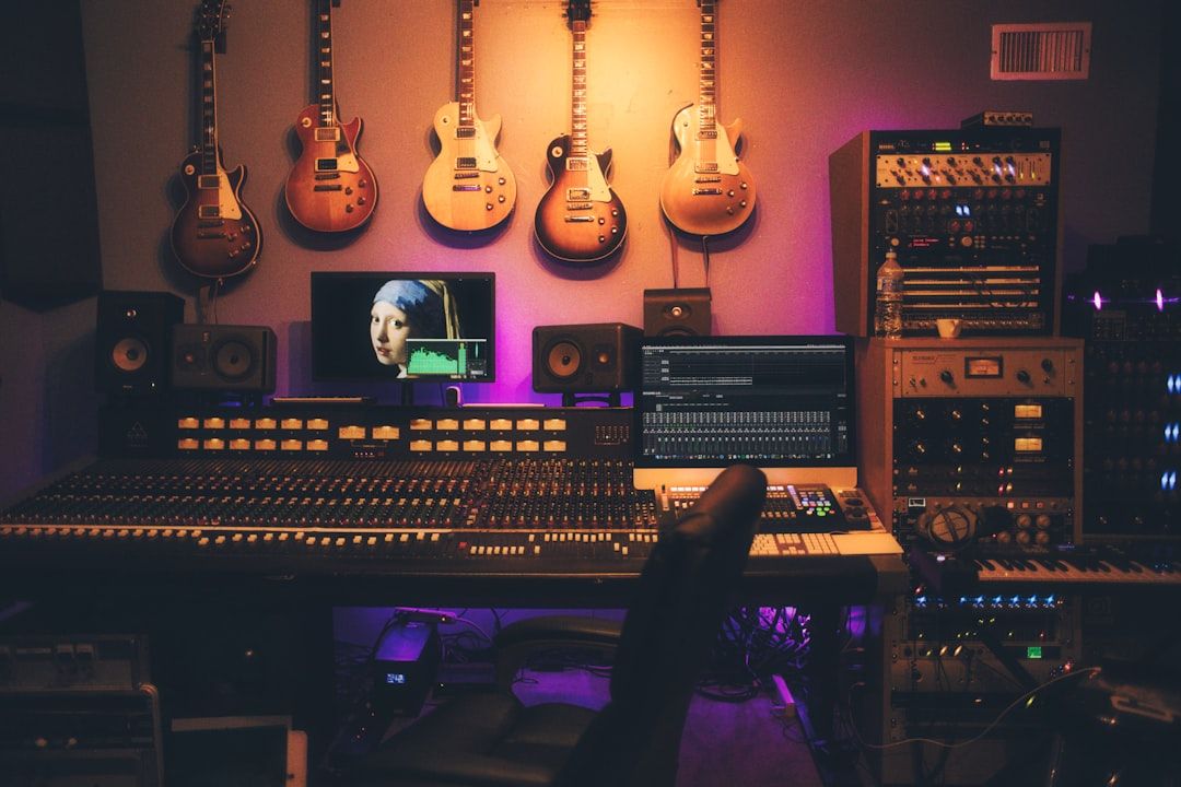 En välutrustad musikstudio med mixerbord, datorskärmar och elgitarrer på väggen.