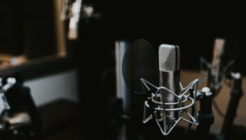 Kondensatormikrofon med popfilter i en mörk podcaststudio