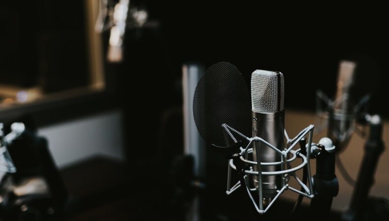 Kondensatormikrofon med popfilter i en mörk podcaststudio